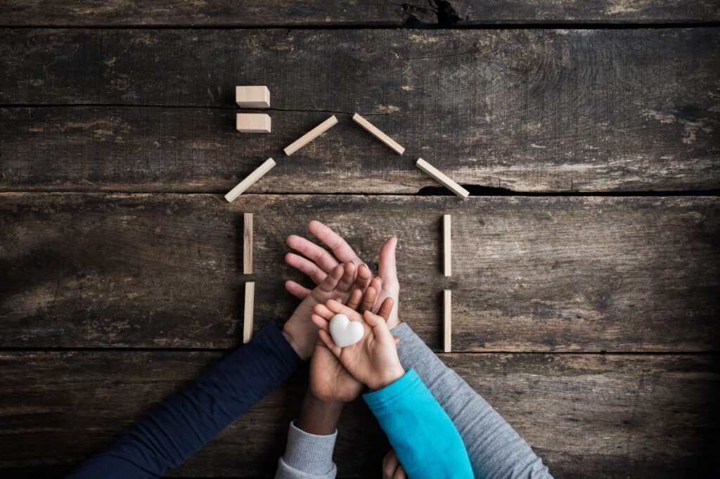 manos de personas sobre silueta de casa